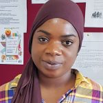 West African woman with plaid yellow shirt and hair scarf