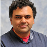 South-East Asian man with curly hair posing for photo with grey background