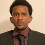 Central-African man with short hair and dark suit posing for photo