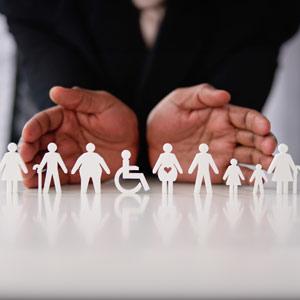 Hands holding a line of diverse paper cut-out figures representing family, health, and inclusion.